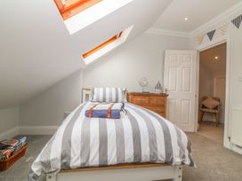 A bedroom with a single bed with striped bedding a wooden dresser and striped chair near the doorway at 7 The Retreat in Paignton