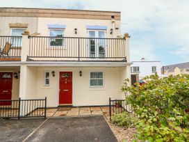 A two-story house with red front doors and a balcony with black railing at 7 The Retreat in Paignton
