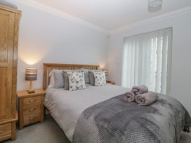 A bedroom with a bed with pillows and folded towels bedside tables with lamps and a wooden wardrobe at 7 The Retreat in Paignton