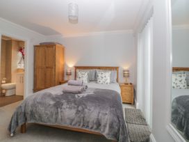A bedroom with a double bed a wooden wardrobe bedside tables with lamps and an ensuite bathroom at 7 The Retreat in Paignton
