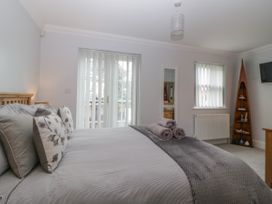 A bedroom with a double bed pillows rolled towels vertical blinds and a wooden shelf at 7 The Retreat in Paignton