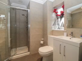 A bathroom with a shower, toilet, sink, and a window with flowers and model sailboats at 7 The Retreat in Paignton