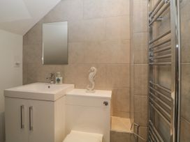 A bathroom with a sink cabinet mirror soap dispenser toilet and heated towel rail at 7 The Retreat in Paignton