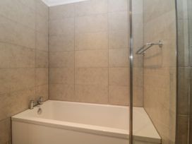 A bathroom with a bathtub surrounded by beige tiled walls and a metal towel bar at 7 The Retreat in Paignton