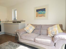 A living room with a sofa and kitchen sink at Little Pippin in Carlyon Bay near St Austell