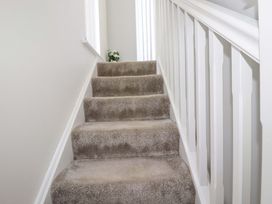A staircase with carpet and railing at Little Pippin in Carlyon Bay near St Austell