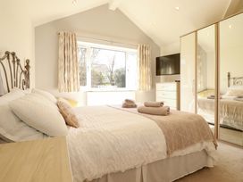A bedroom with a bed, dresser, and television at Little Pippin Carlyon Bay near St Austell