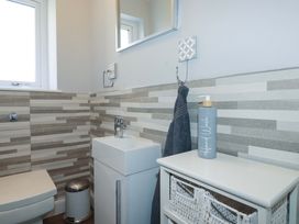 A bathroom with toilet, sink, and hand wash at Little Pippin Carlyon Bay near St Austell