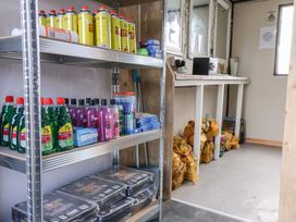 A storage room with shelves containing cleaning products and various items at Stable Cottage in Staintondale