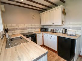 A kitchen with a sink, oven, toaster, kettle, and fridge at Stable Cottage in Staintondale near Burniston