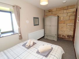 A bedroom with a bed and wardrobe at Stable Cottage Staintondale near Burniston