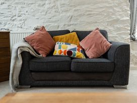 A sofa with cushions and a blanket at The Coach House Llangollen