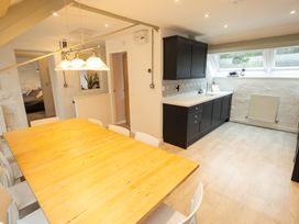 A dining room with a table, chairs, and kitchen cabinetry at The Coach House in Llangollen