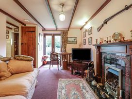 A living room with a sofa table and chairs a TV and a fireplace with decor at Hafoty Boeth Cottage Corwen