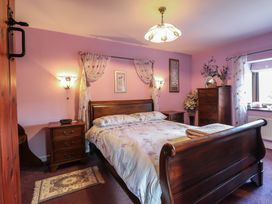 A bedroom with a wooden bed and bedside tables with lamps and purple walls at Hafoty Boeth Cottage in Corwen