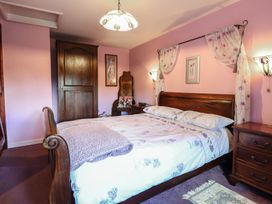 A bedroom with a wooden bed and pink walls at Hafoty Boeth Cottage in Corwen