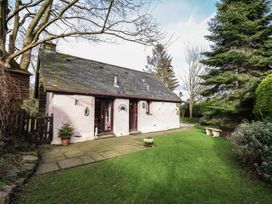 A small cottage with a slate roof surrounded by trees and grass at Hafoty Boeth Cottage in Corwen