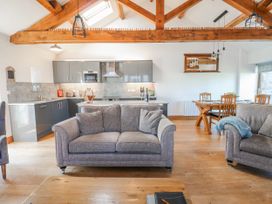 A living room with a sofa and kitchen area at Apple Tree Cottage Bleatarn near Kirkby Stephen