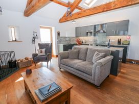 A living room with a sofa and kitchen area at Apple Tree Cottage near Bleatarn near Kirkby Stephen