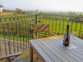 A balcony with a table, glasses, and a bottle at Apple Tree Cottage in Bleatarn near Kirkby Stephen