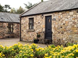 A stone cottage with a door and flowers at Blueberry Cottage in Akeld near Wooler