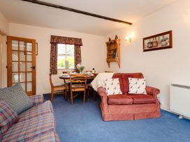 A living room with a sofa and dining area at Blueberry Cottage in Akeld near Wooler