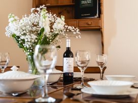 A dining table set with dishes and a wine bottle at Blueberry Cottage in Akeld near Wooler