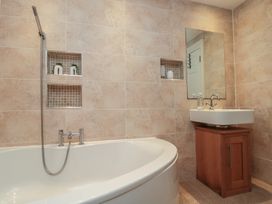 A bathroom with a bathtub and sink with a mirror at Apartment 6 in Whitby