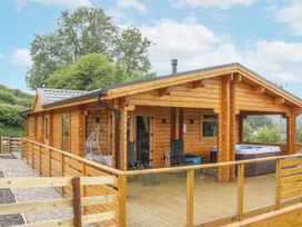 A wooden lodge with a deck and hot tub at Manor Farm Lodges - Red Kite Lodge in Newtown