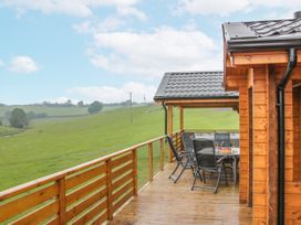 An outdoor deck with table and chairs at Manor Farm Lodges - Dragon Lodge, Newtown