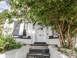 The front entrance of a white house with black trim and a tree on each side of the steps at Eversley in Llandudno