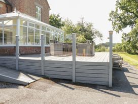 An outdoor deck area with a conservatory and seating at Maes Elwy in St Asaph