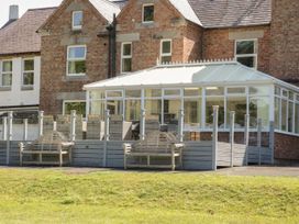 A conservatory with benches and grass at Maes Elwy in St Asaph
