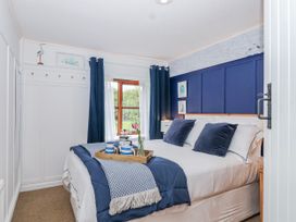A bedroom with a bed and window at Lily Cottage in Looe