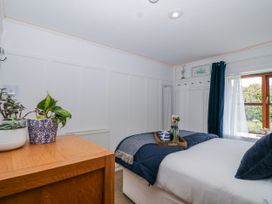 A bedroom with a bed and plants at Lily Cottage in Looe