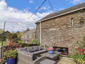An outdoor seating area with a couch and flower pots at Lily Cottage in Looe