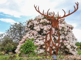 A deer sculpture in front of a flowering bush at Lily Cottage in Looe