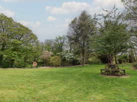 A garden with grass and a picnic table at Lily Cottage in Looe