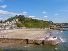 A beach with a pier and houses on the cliff at Lily Cottage in Looe