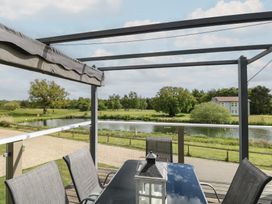 An outdoor area with a table and chairs overlooking a lake at Links View in Fritton
