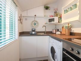 A kitchen with a sink, stove, and microwave at Smugglers Cottage near Trebarwith Strand