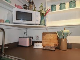 A kitchen with a microwave, toaster, and utensils container at Smugglers Cottage Trebarwith Strand near Tintagel