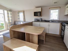 A kitchen with table, bench, microwave, and stove at K2 Static Caravan