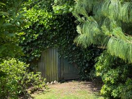 A garden with a green door surrounded by ivy and pine trees at Penlaurel in Launceston