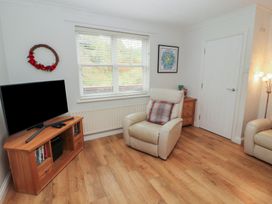 A living room with a television and armchair at Riverside Cottage in Cockermouth