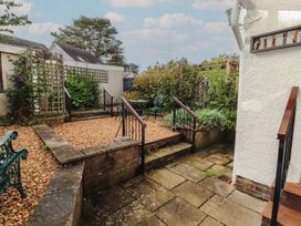 A garden area with gravel, steps, green furniture and plants at Riverside Cottage in Cockermouth