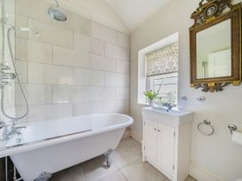 A bathroom with a bathtub, sink, and mirror at Mappowder Cottage in Buckland Newton near Dorchester