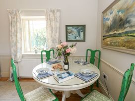 A dining room with a round table and green chairs at Mappowder Cottage Buckland Newton near Dorchester