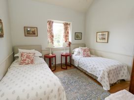 A bedroom with two beds and a window at Mappowder Cottage in Buckland Newton near Dorchester