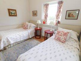 A bedroom with two single beds and bedside tables at Mappowder Cottage in Buckland Newton near Dorchester